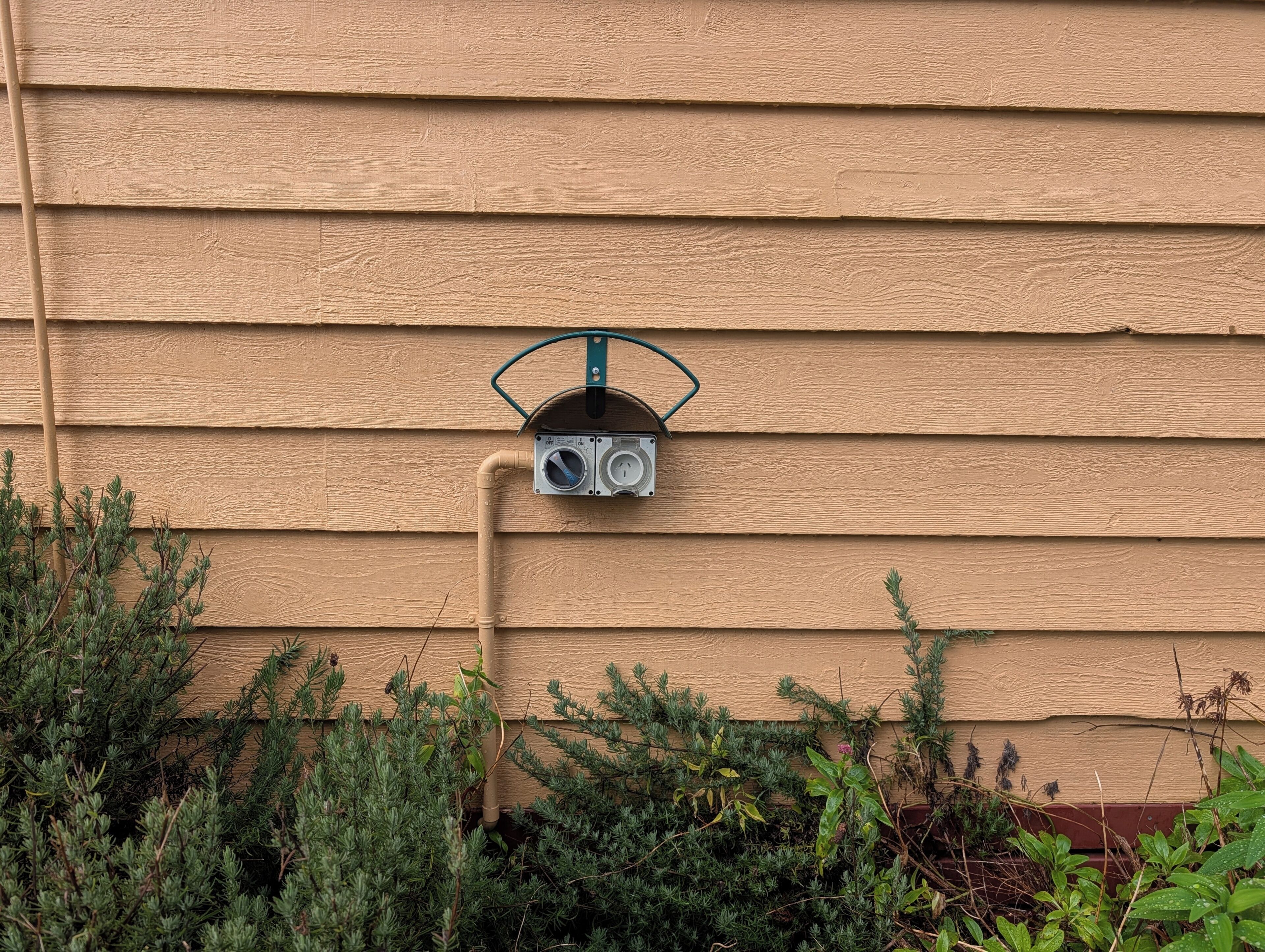 A utility meter attached to a beige wooden house siding.