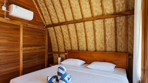 A room with a wooden ceiling, a bed with white bedding, and a wall-mounted air conditioning unit. - Cozzy Bilva Garden (Klungkung)