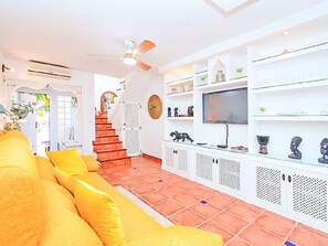 En stue med sofa, tv og reoler med dekorative genstande.