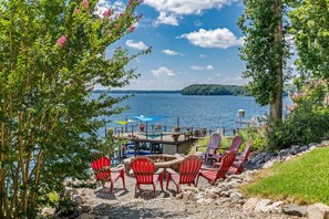Une terrasse au bord du lac, avec des fauteuils Adirondack, un foyer et une vue sur le lac.