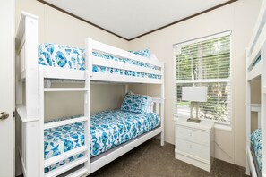 Une chambre avec un lit superposé, une fenêtre et une commode.