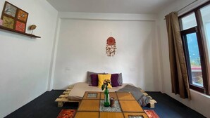 A bedroom with a bed, a hanging decoration, a window with curtains, and a wall-mounted shelf with a framed picture. - Elevn Stays, Manali (Manali)
