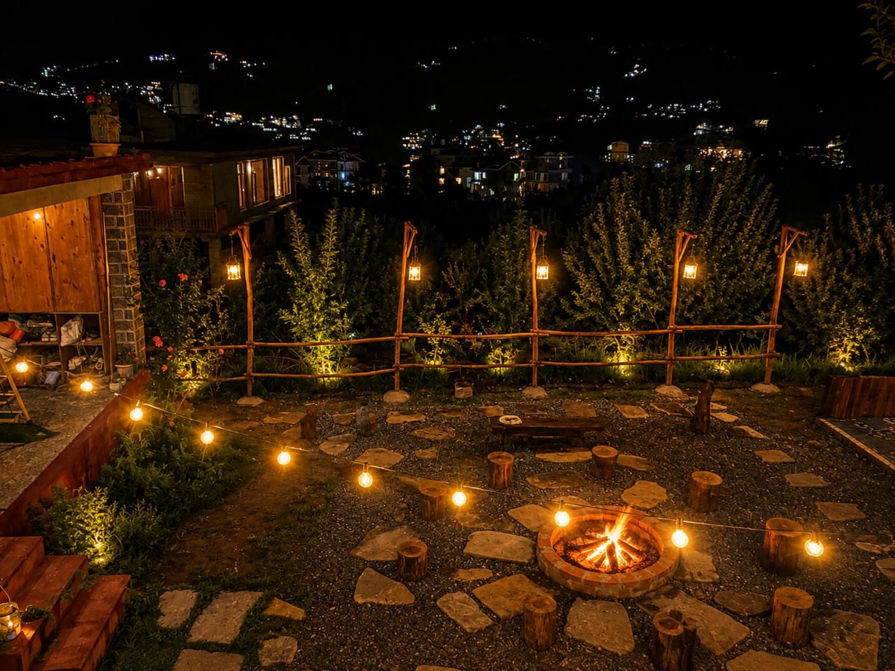 Un espace extérieur aménagé en terrasse, avec un foyer, des guirlandes lumineuses et une plateforme en bois.