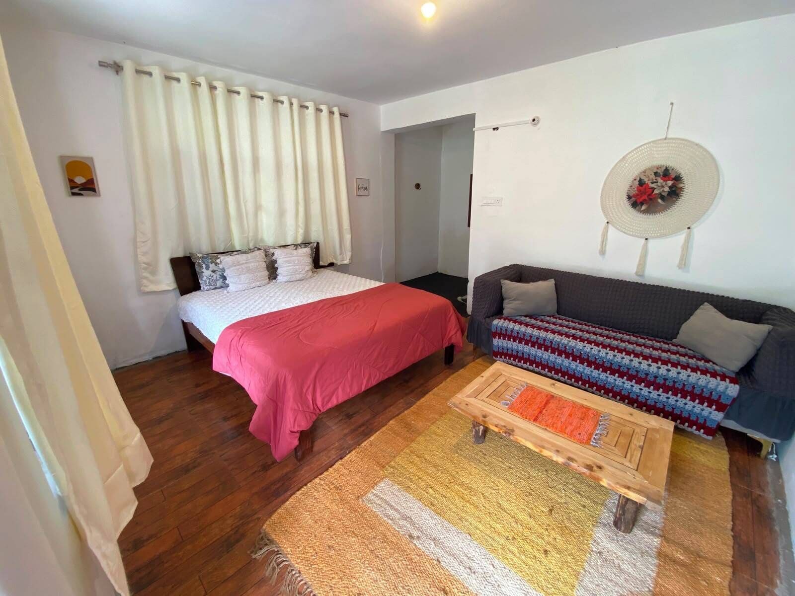 A bedroom with a bed, a sofa, a small table, and a wall-mounted decorative item.