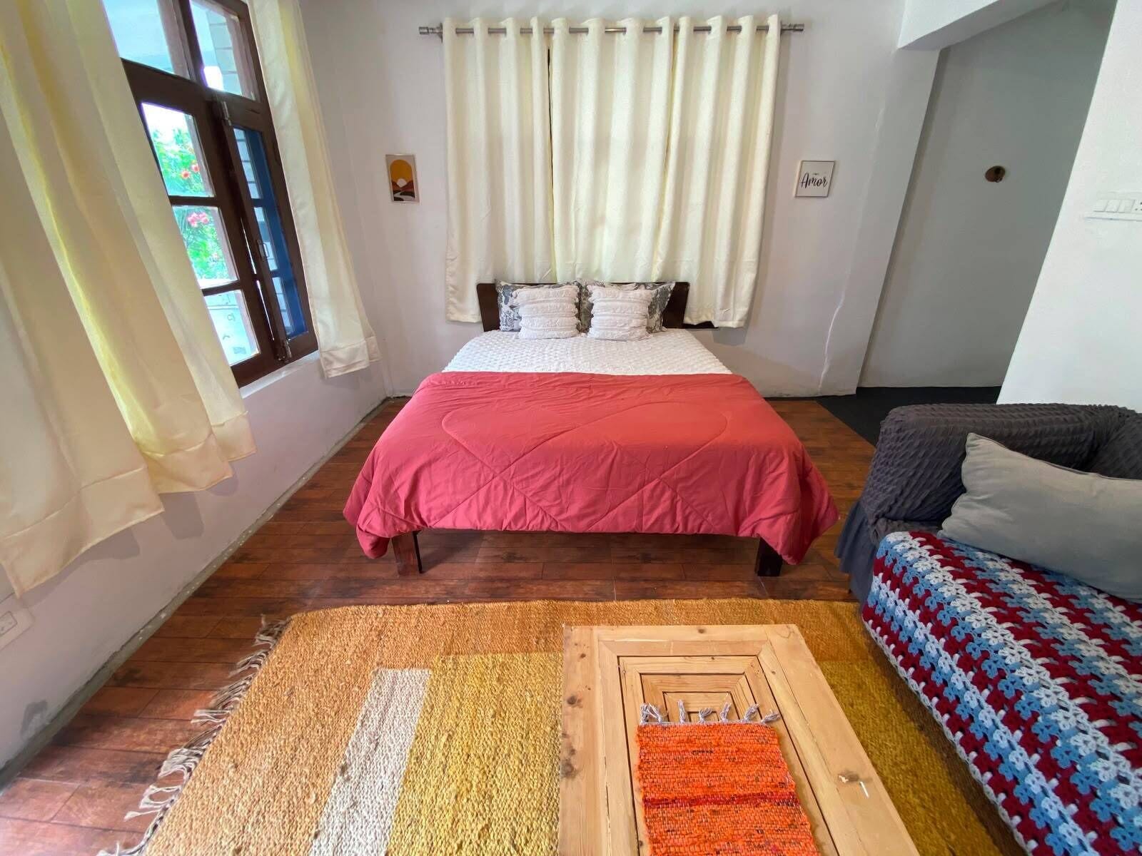 A bedroom with a bed, a sofa, and a patterned rug.