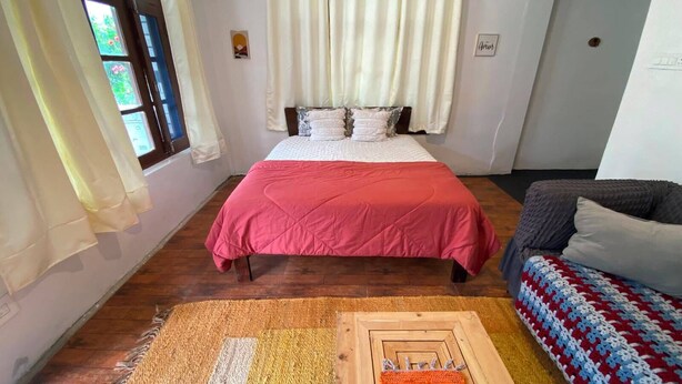 A bedroom with a bed, a sofa, and a patterned rug. - Elevn Stays, Manali (Manali)