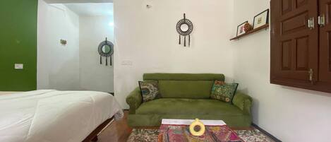 A room with a green sofa, a bed, a patterned rug, and a wall with two circular wall decorations.