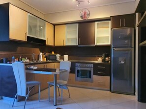 A modern kitchen with a central island, stainless steel appliances, and a dining area with chairs. - Quiet apartment in Artemis, Athens Airport (Artemis)