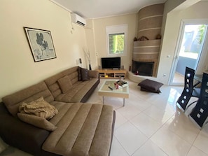 A living room with a sofa, a coffee table, a fireplace, and a TV. - Quiet apartment in Artemis, Athens Airport (Artemis)