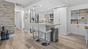 Una cocina moderna con una isla central, electrodomésticos de acero inoxidable y una zona de asientos con taburetes de bar.