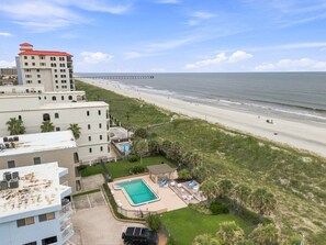 Ein Strandhotel mit Pool, direktem Strandzugang und einem Pier im Hintergrund.
