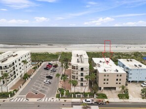 A beachfront hotel with multiple floors, a parking lot, and a view of the ocean. - 2BR Steps to Beach & Pool | Good Morning Rentals (Jacksonville Beach)