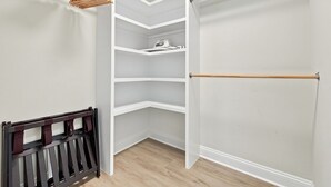 A walk-in closet with open shelving, a hanging rod, and a wooden bench. - Modern 3BR Near Beach | Good Morning Rentals (Jacksonville Beach)