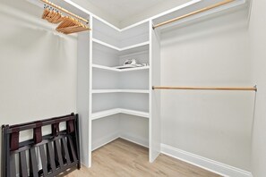 Ein begehbarer Kleiderschrank mit offenen Regalen, einer Kleiderstange und einer hölzernen Sitzbank.
