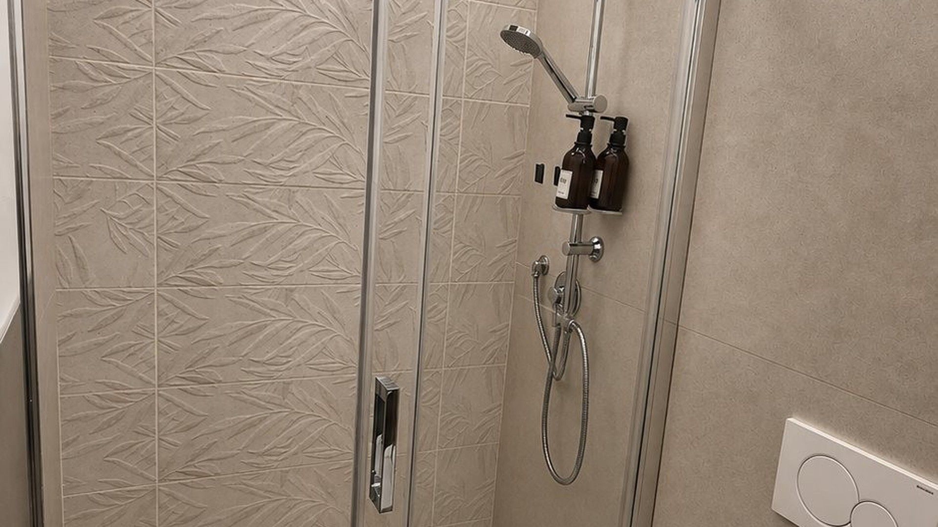 Ducha con cabezal de ducha de mano y panel de control en la pared.