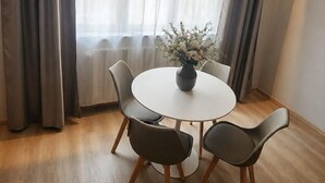 A dining area with a round table, four chairs, and a vase of flowers. - ROOM 1 Studio apartment near downtown and the train station, with private parking (TORINO)