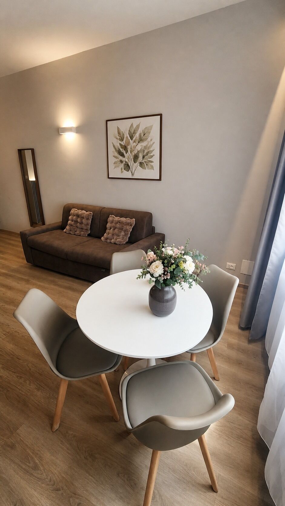 Un salon moderne avec un canapé, une table ronde et deux chaises.