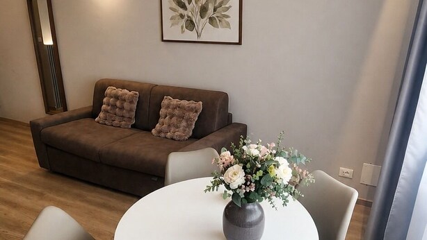 A modern living room with a sofa, a round table, and two chairs. - ROOM 1 Studio apartment near downtown and the train station, with private parking (TORINO)