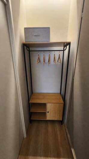 Een kast met een houten bankje, een kledingroede en een plank.
