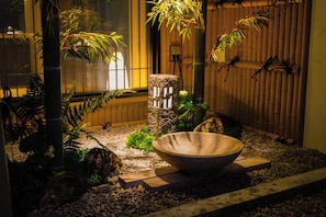A traditional Japanese garden with a stone basin, bamboo plants, and a wooden fence. - Konjaku-so Osaka Dotonbori - Bookstore - (大阪市中央区道頓堀１丁目東)