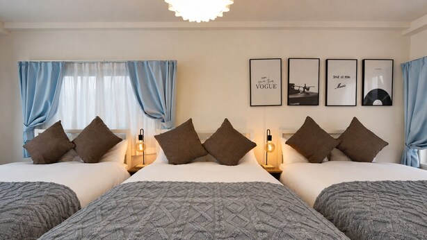 Quarto de hotel com uma cama grande, duas mesas de cabeceira, uma parede com quadros e cortinas azuis.