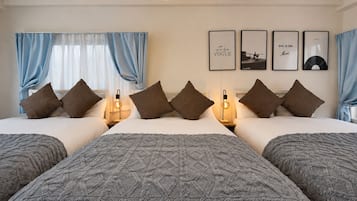 A hotel room with a large bed, two bedside tables, a wall with framed pictures, and blue curtains.