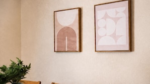 Uma sala de jantar com uma mesa, cadeiras e duas obras de arte emolduradas na parede.