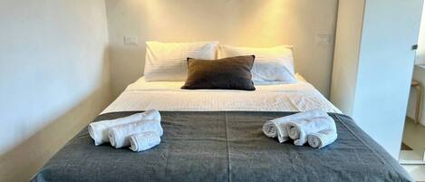 Een hotelkamer met een bed, kussens en handdoeken.