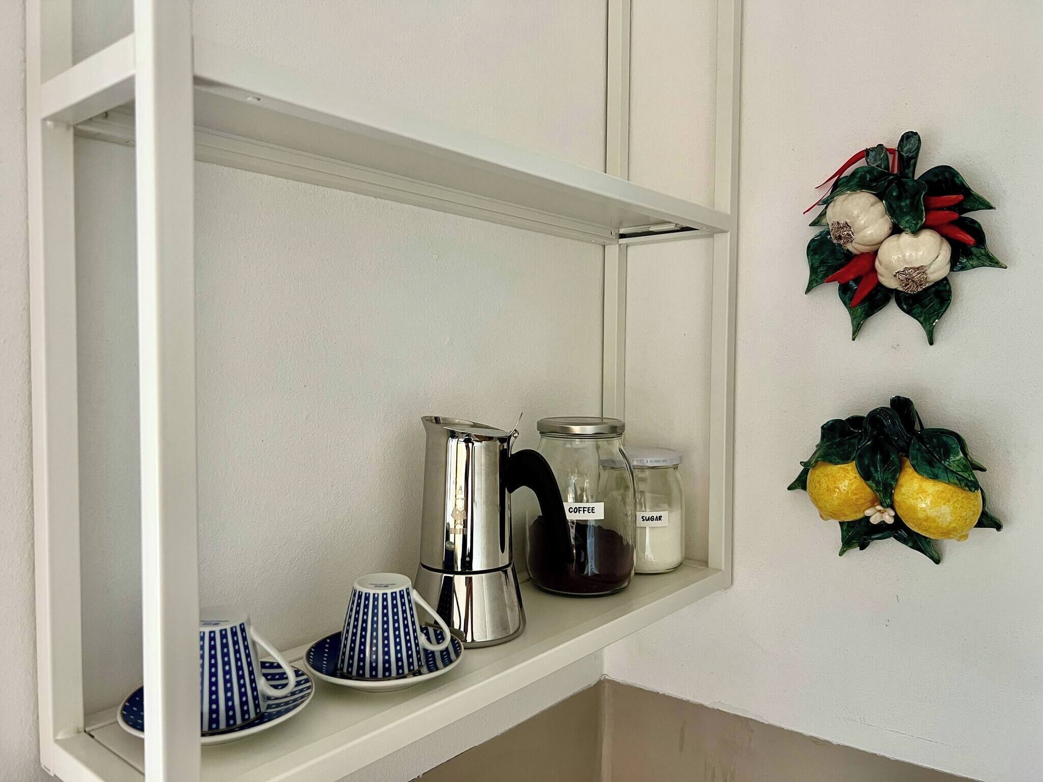 Ein Küchenregal mit einer Kaffeemaschine, einer Zuckerlösung und einer dekorativen Wanddekoration.