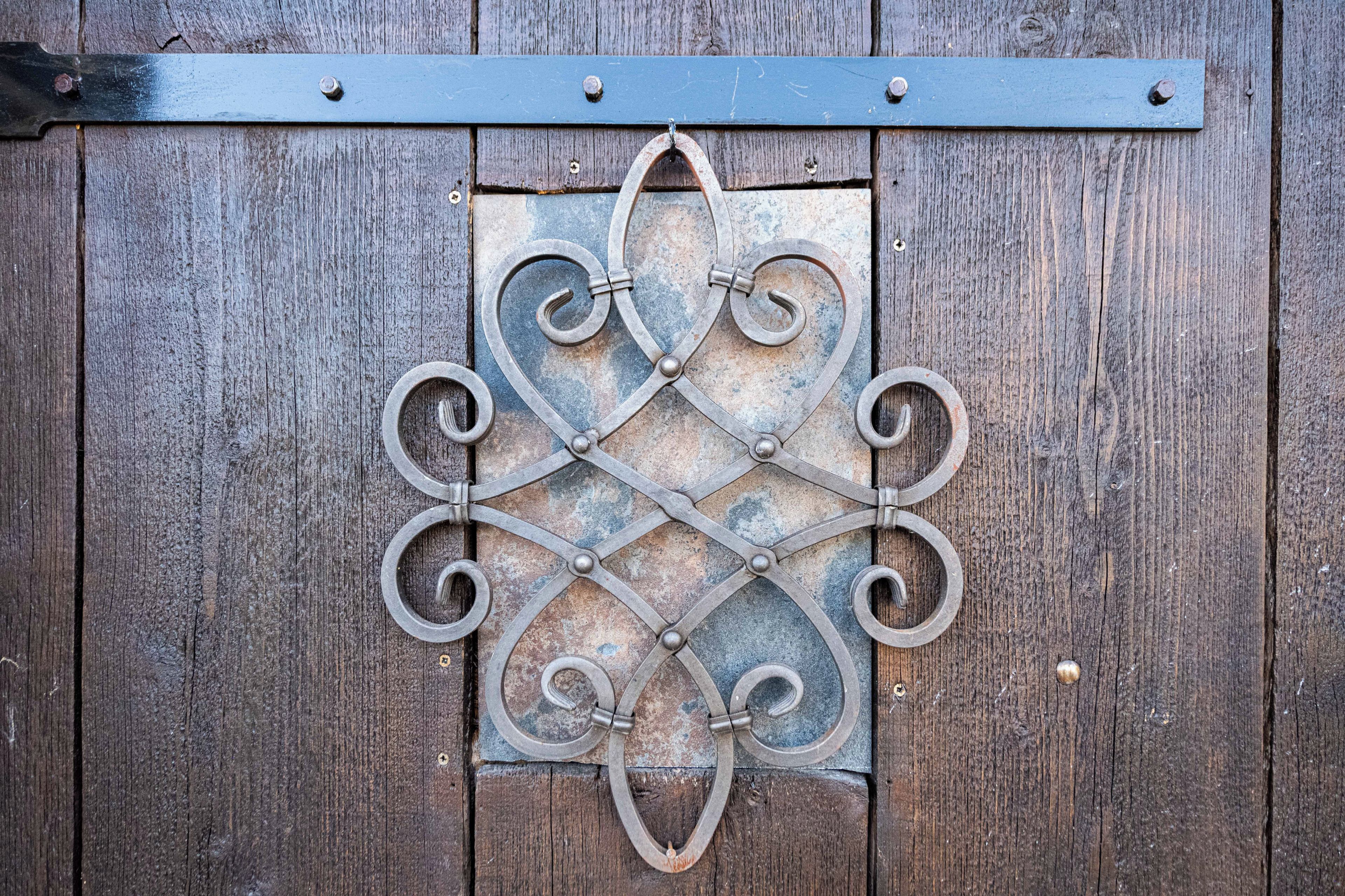 A metal decorative piece with a geometric pattern, mounted on a wooden surface.