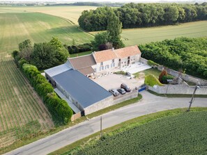 A large, single-story stone building with a tiled roof, surrounded by expansive fields and trees. - Immersive Medieval Cottage - Private wellness area (Soisy-Bouy)