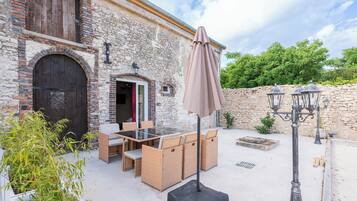 Un espace extérieur aménagé avec des meubles en osier, une table et un parasol.