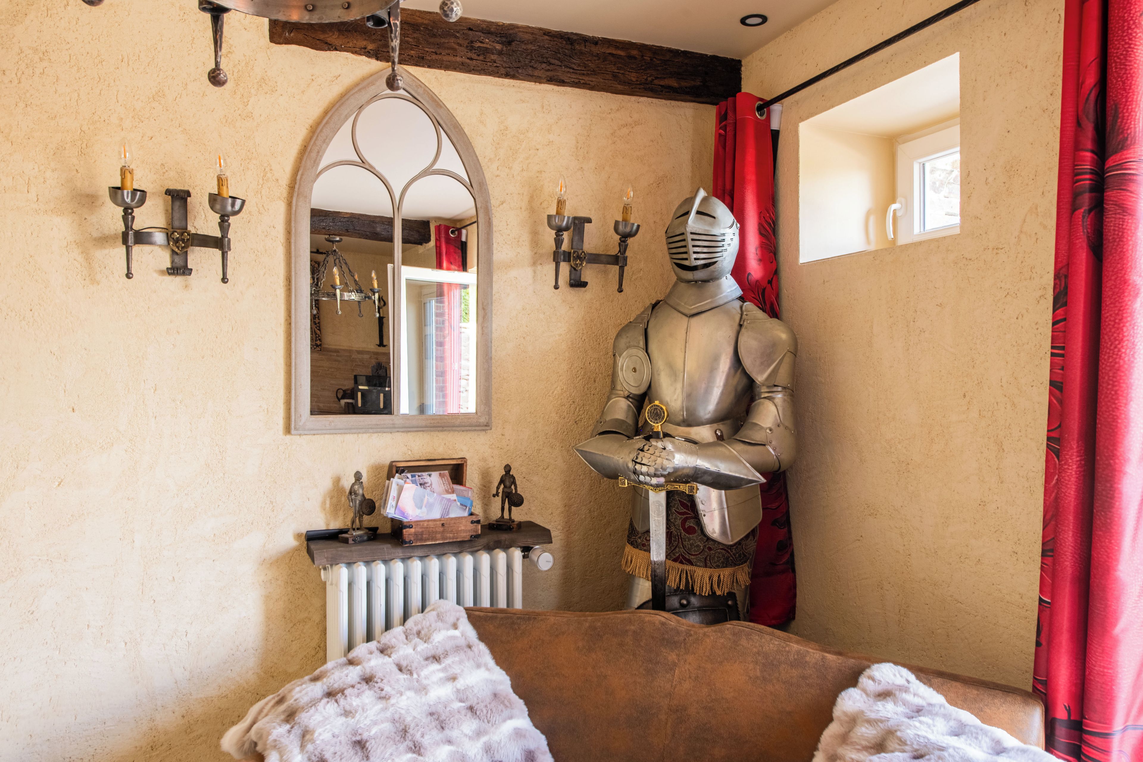 A medieval-themed room with a knight statue, a mirror, and a radiator.