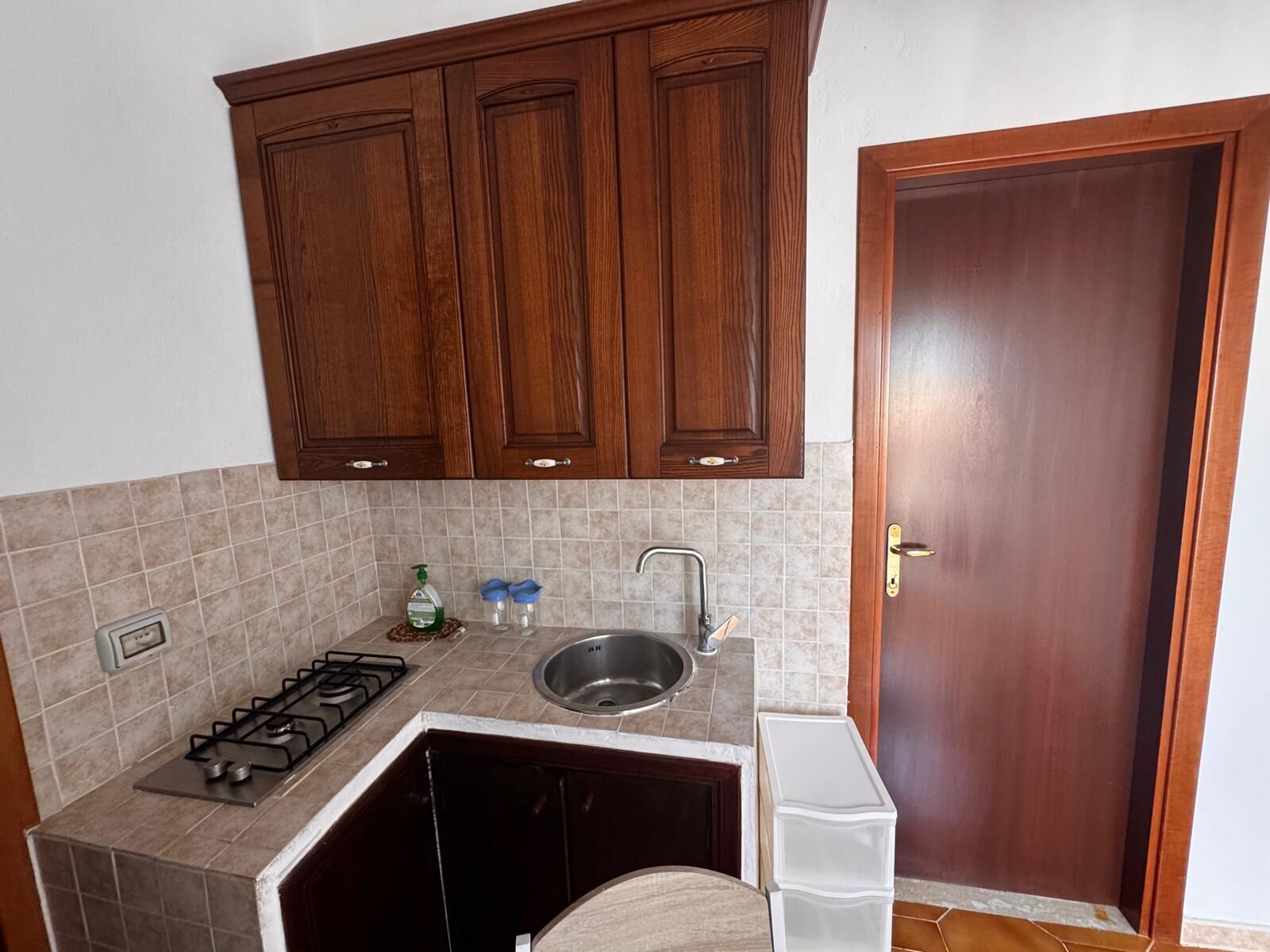 Uma cozinha compacta com fogão a gás, pia e armários de madeira.