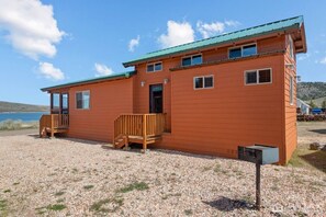 A two-story wooden cabin with a porch, a small deck, and a view of the water. - Fisherman’s Paradise 2 | Panguitch Lakefront Cabin (Panguitch)