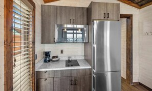 Eine kompakte Küche mit einem Edelstahl-Kühlschrank, einem eingebauten Backofen und einer Kaffeemaschine auf der Arbeitsplatte.