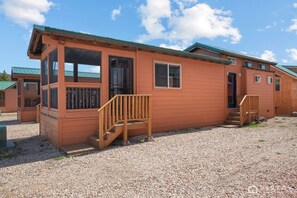Eine einstöckige Holzhütte mit Veranda, Tür und Fenster.