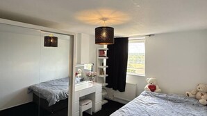 A bedroom with a bed, a desk, a mirror, and a window. - Apartment Sleeps 2 With Free Parking (Orpington)