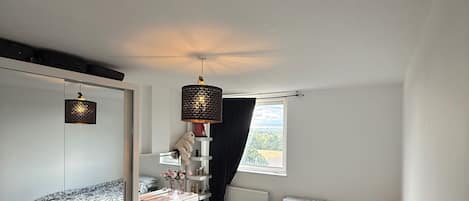 A bedroom with two beds, a dresser, a mirror, and a hanging light fixture.
