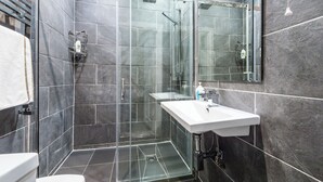 Une salle de bain moderne avec une douche à parois de verre, un lavabo blanc et un grand miroir.