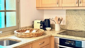 Une cuisine avec des meubles en bois, un évier en acier inoxydable, un grille-pain et une bouilloire.