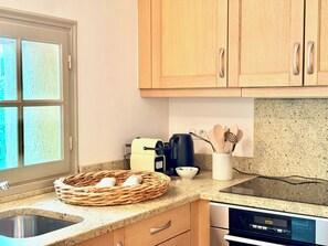 A kitchen with wooden cabinets, a stainless steel sink, a toaster, and a kettle. - Le Bastidon (La Garde-Freinet)