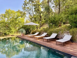 A poolside area with lounge chairs and a wooden deck. - Le Bastidon (La Garde-Freinet)