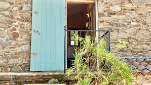 Un bâtiment en pierre avec une porte bleue et un petit balcon.