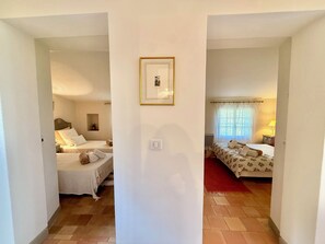 Quarto de hotel com duas camas, um quadro na parede e uma janela com cortinas.