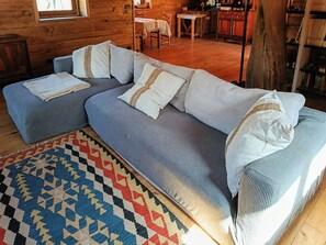 Ein gemütliches Wohnzimmer mit einem Ecksofa, einem gemusterten Teppich und Holzböden.