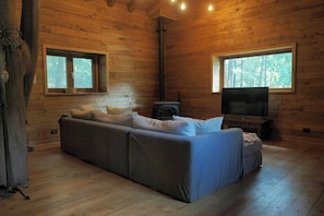 A log cabin interior with a sofa, a television, and a fireplace. - Handbuilt home in the wild Ligurian hills (Pontinvrea)
