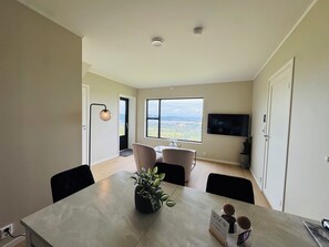 Un comedor moderno con una mesa, sillas, una planta en maceta y vistas al exterior.