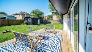 Une terrasse dotée de mobilier d’extérieur et d’un tapis à motifs.