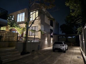 Ein modernes Gebäude mit großen Fenstern, ein Auto davor und ein Baum im Vordergrund.